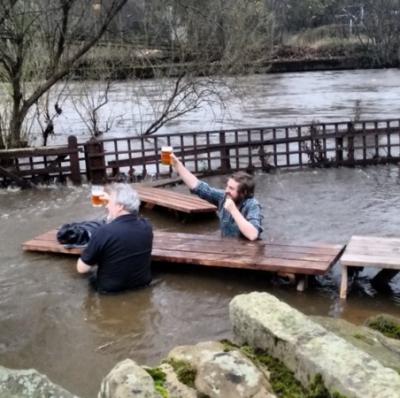 Mannen drinken bier ondanks overstroming